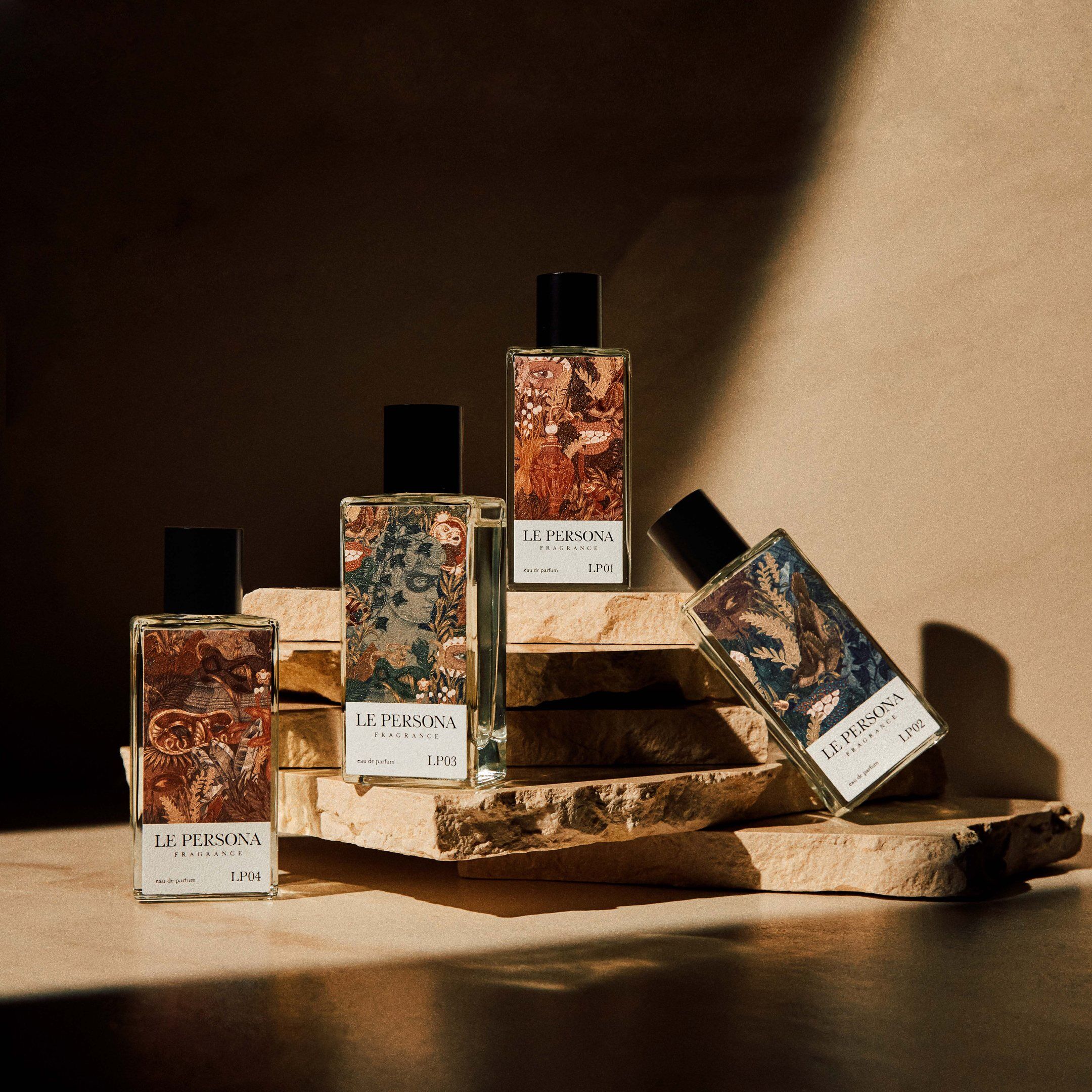 A group of the La Persona perfume bottles arranged on slabs of rock