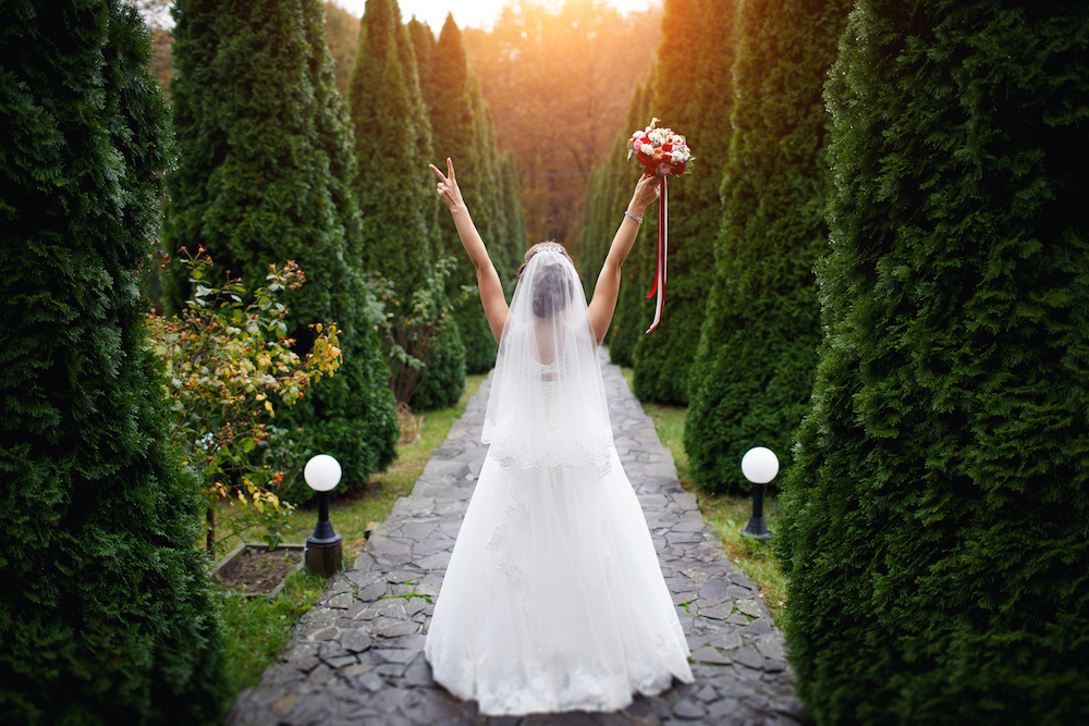 wedding bride with flowers amidst cypress trees