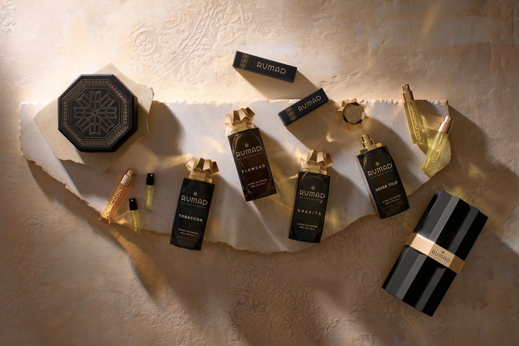 A group of Rumad fragrances laid against pale stone backdrop