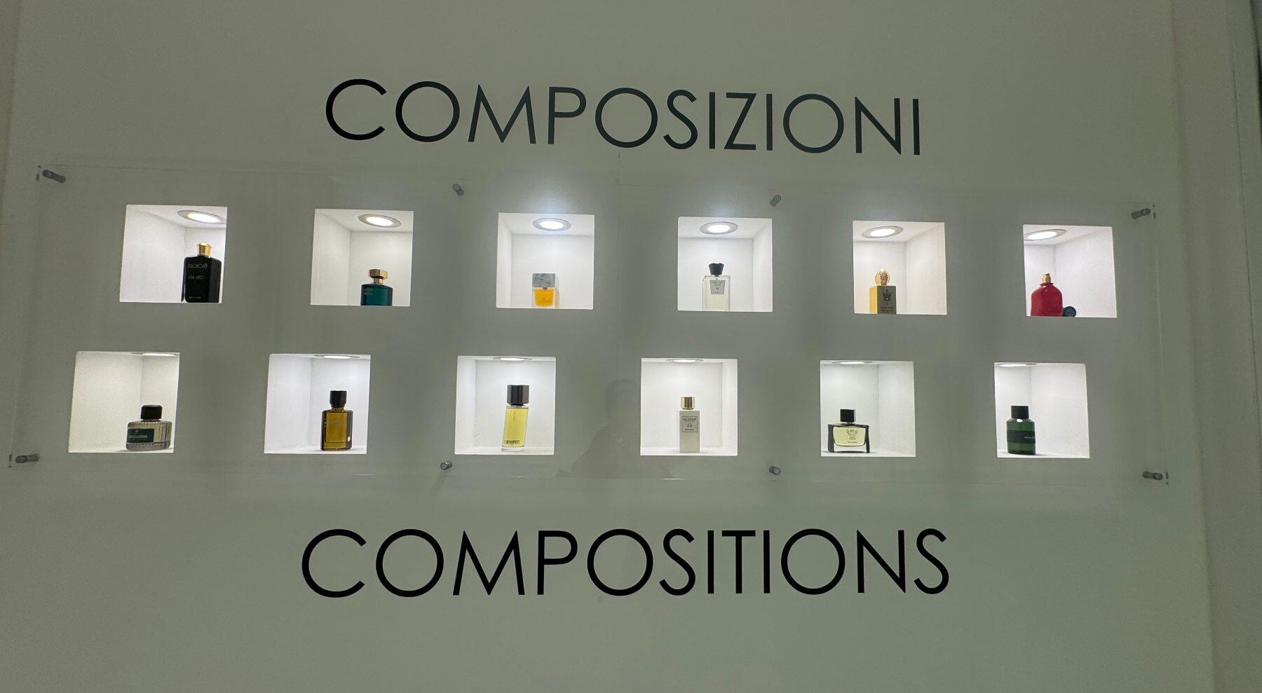A wall showing the word compositions with an array of perfumes in small lighted niches
