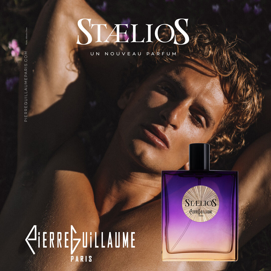 Staelios perfume advertising image of a man laid on a bed of flowers. He has tanned skin and looks seductively at the camera