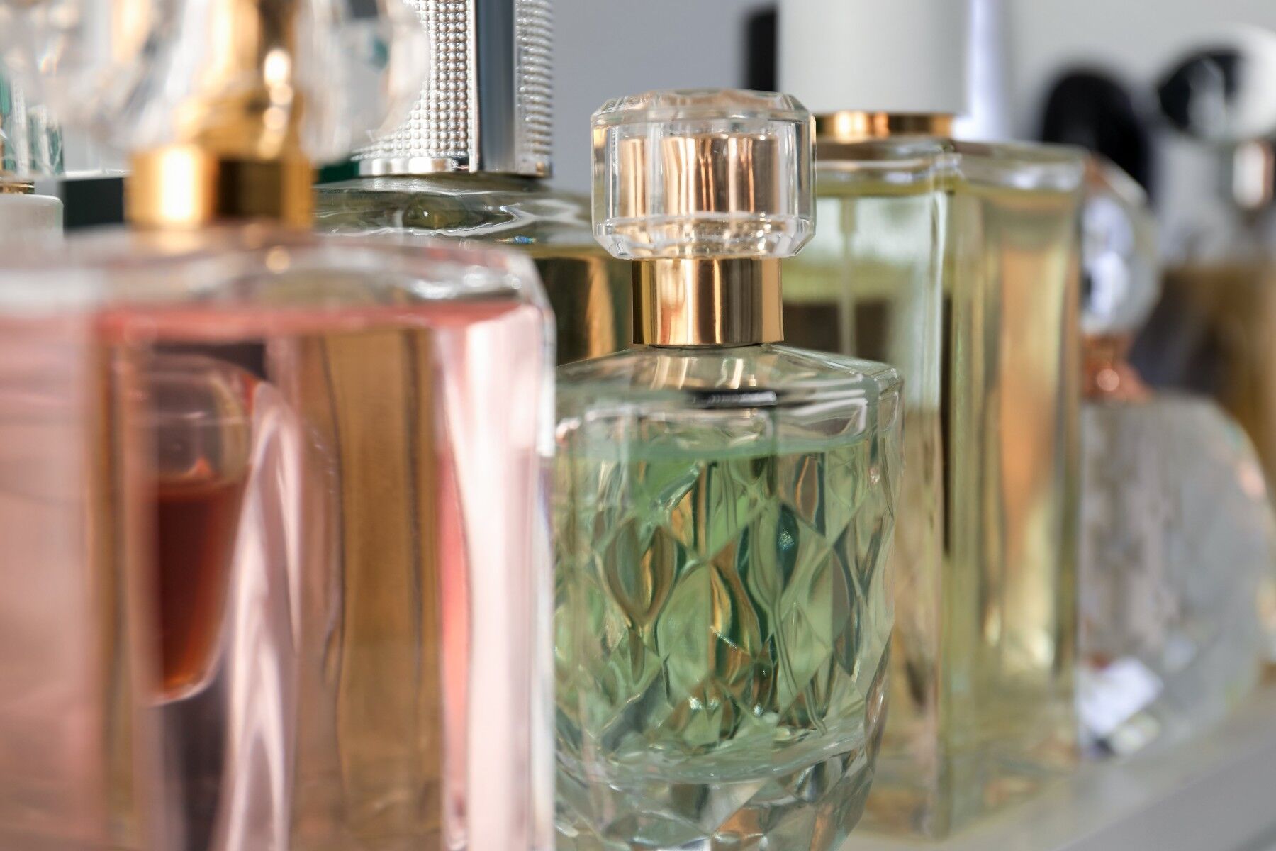 A group of perfume bottles on a shelf, they are all different sizes and colours