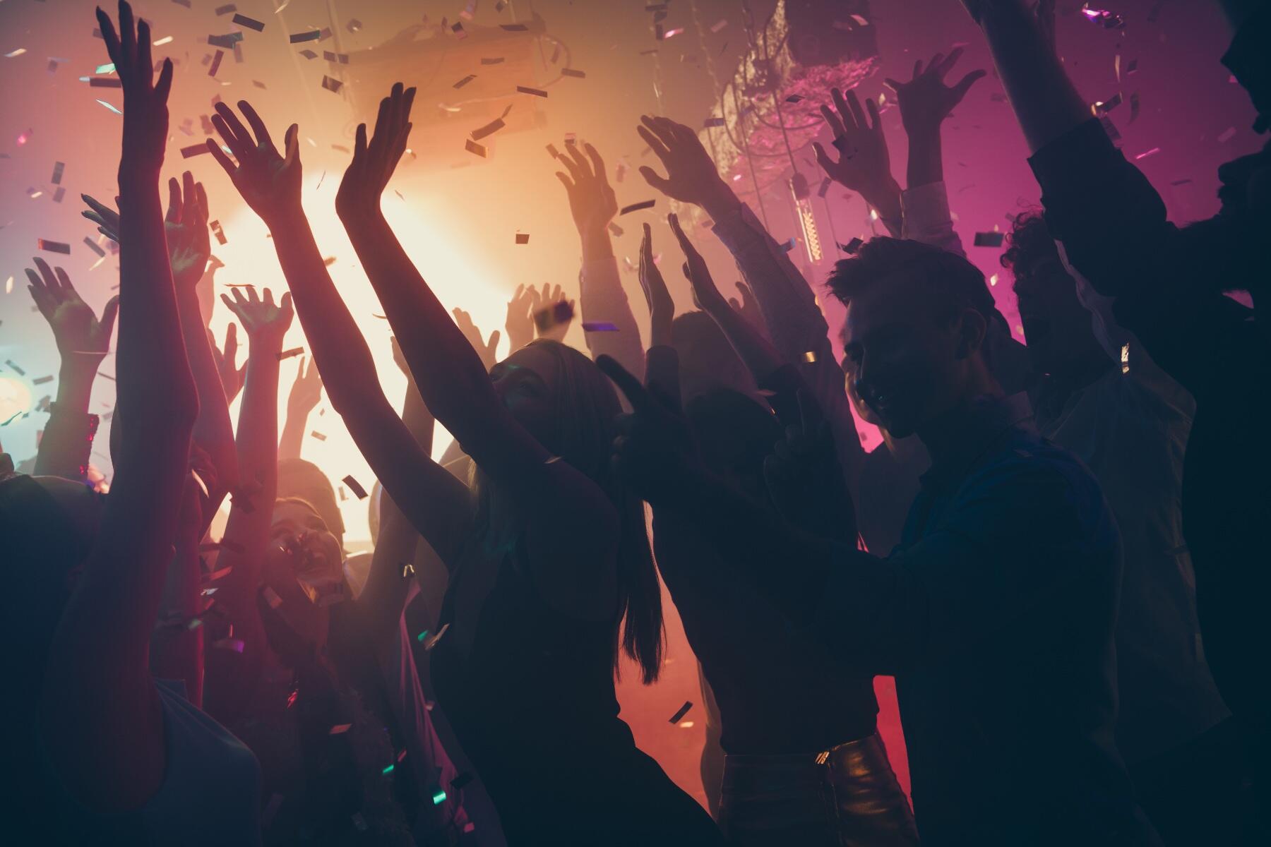 Silhouettes of people in a club with orange and purple light behind