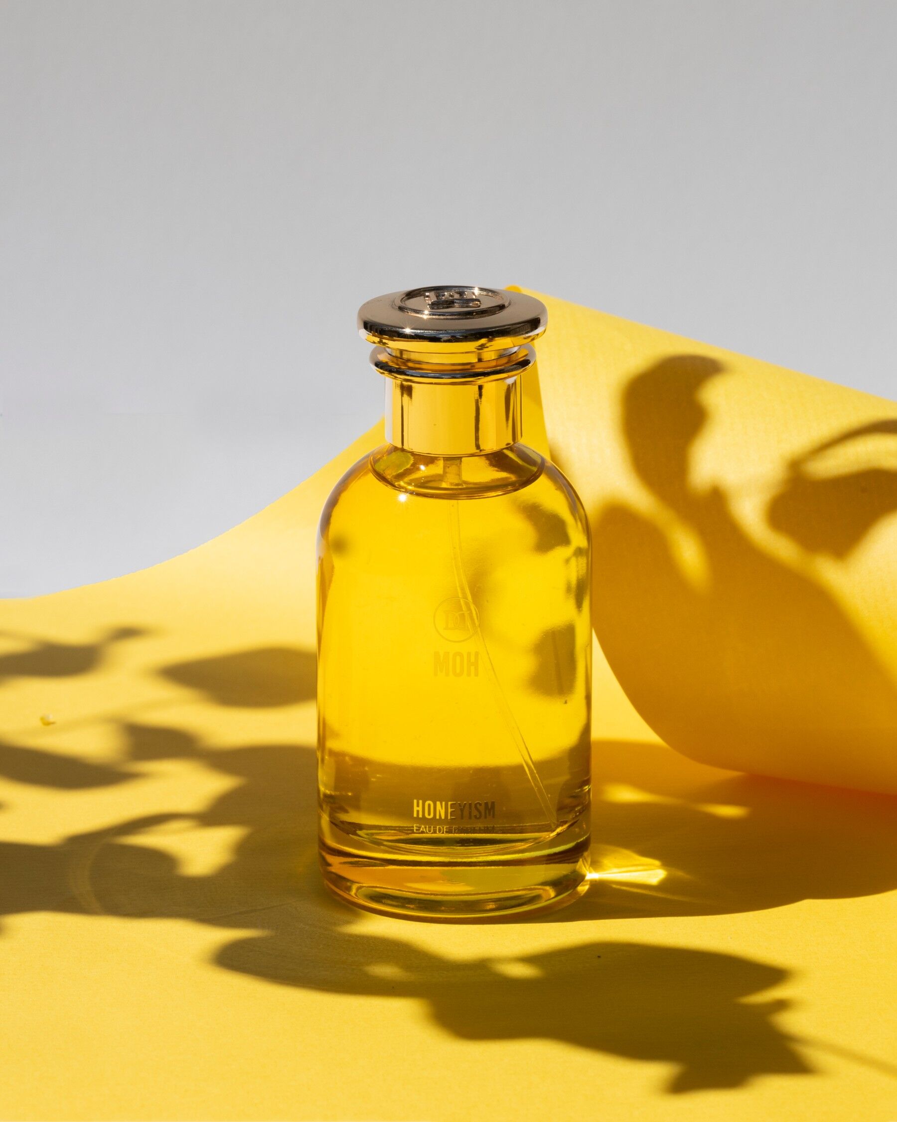 A bottle of Honeyism stood on yellow with sunlight