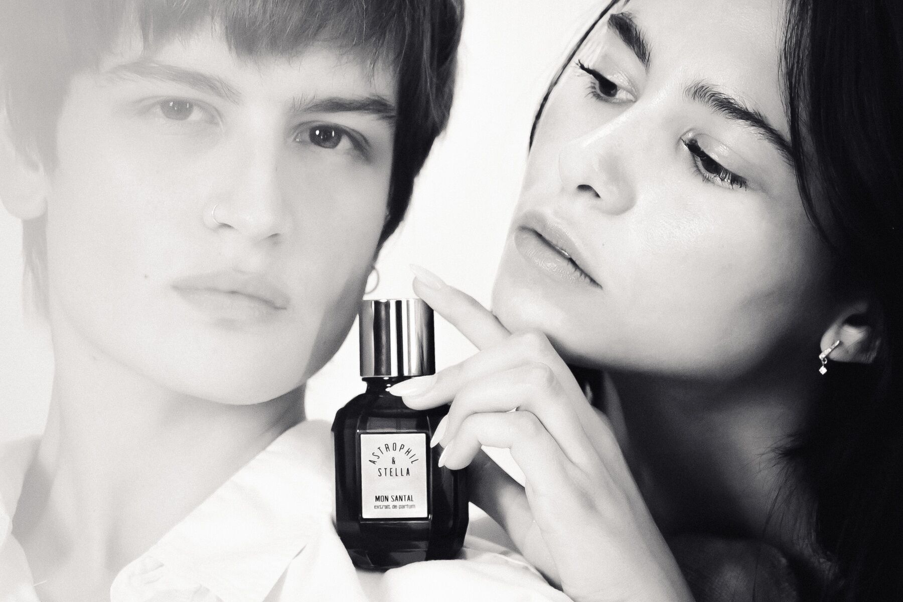 A man and woman in black and white holding a bottle of Mon Santal