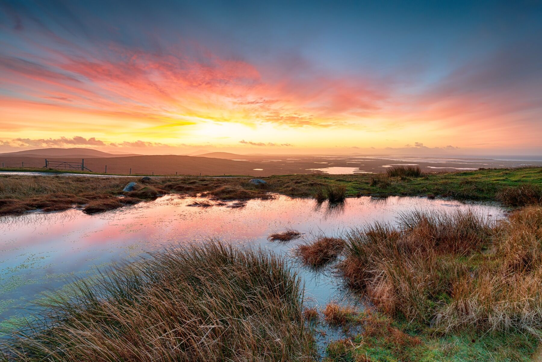 A landscape showing a peat bog under a stunning sunset