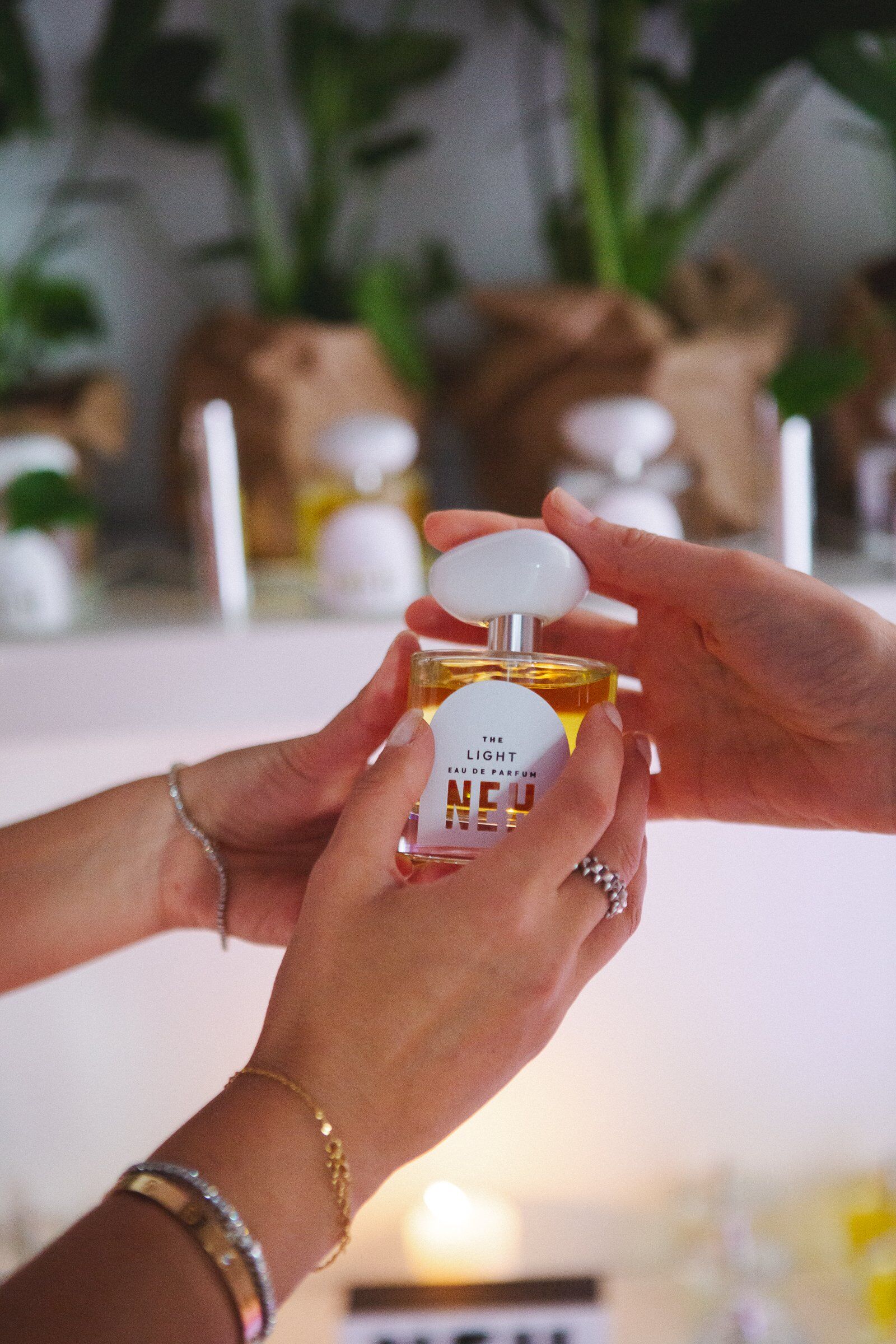 A bottle of Neh perfume being passed between hands