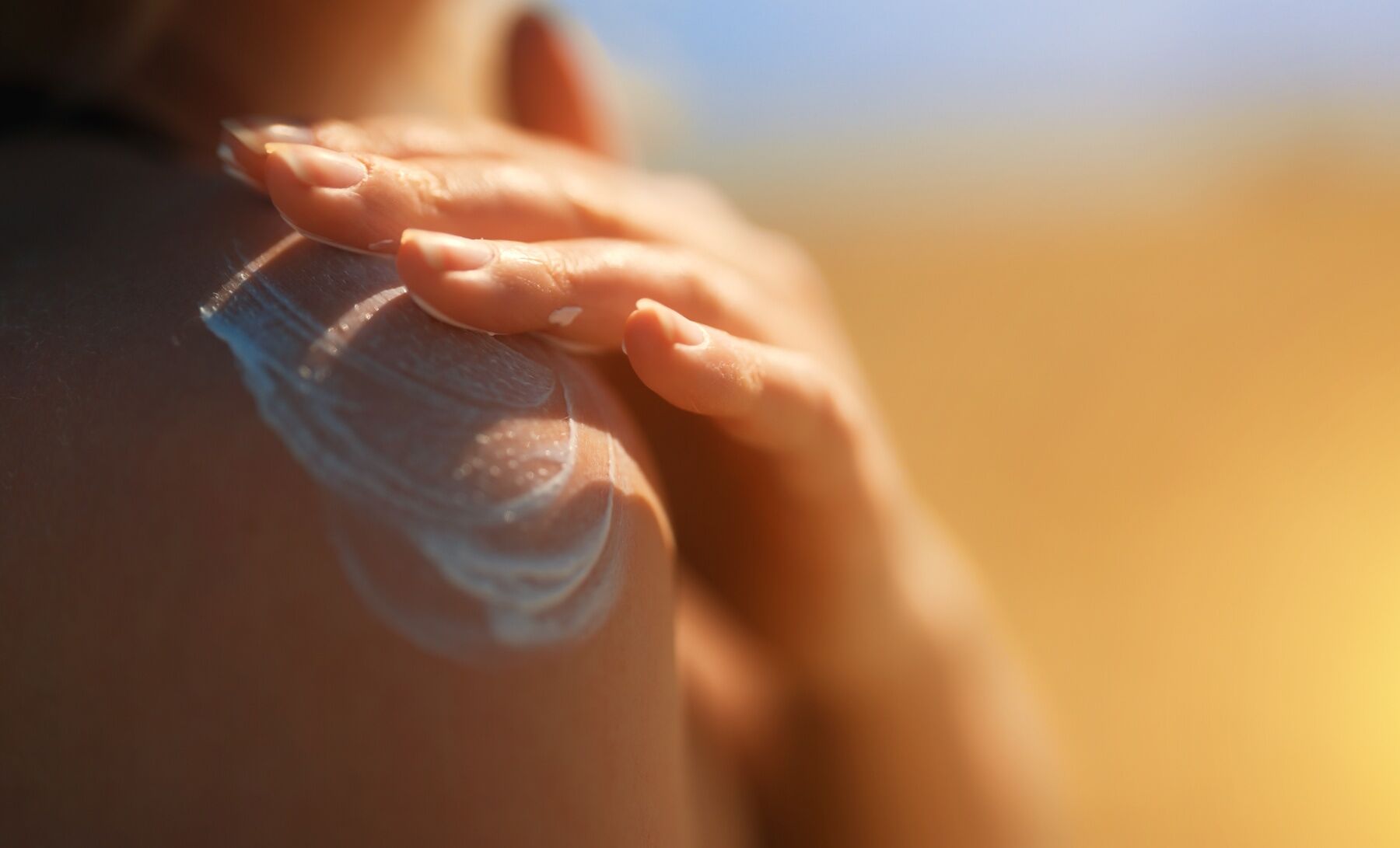 A woman applying sun cream to her shoulder