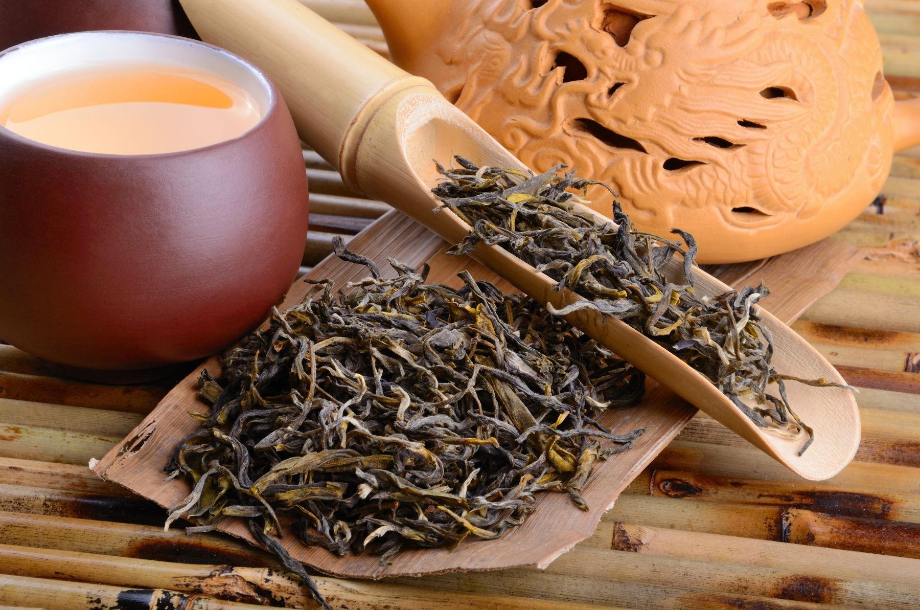 cup and pot with tea and dried tea leaves