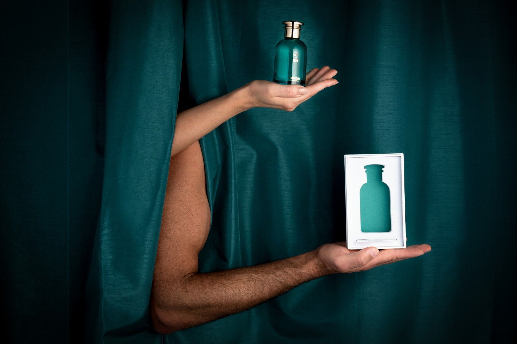 A male and a female arm poking through a green curtain to show that this scent is unisex