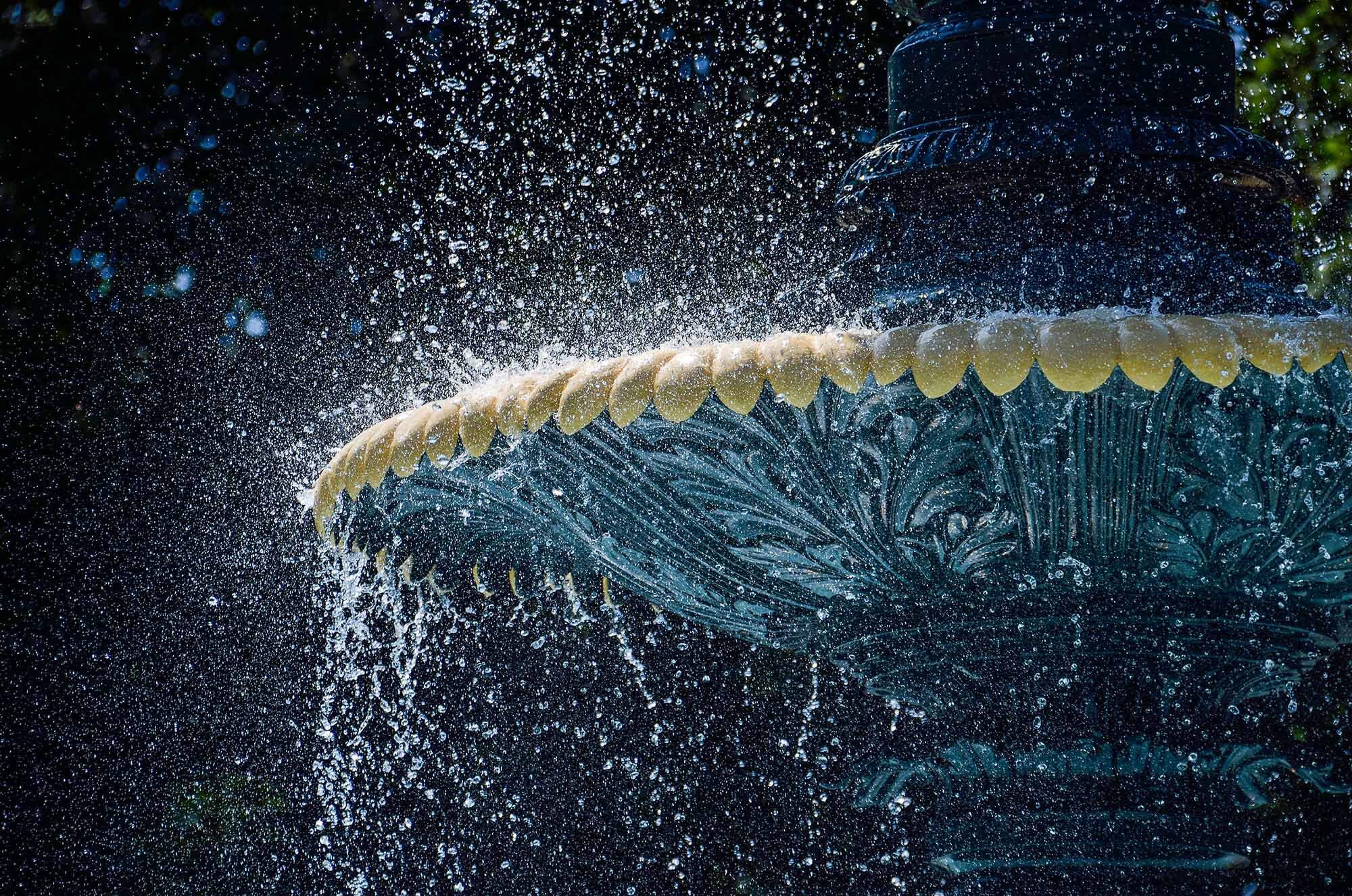 The edge of an Italian water fountain with spray of water.