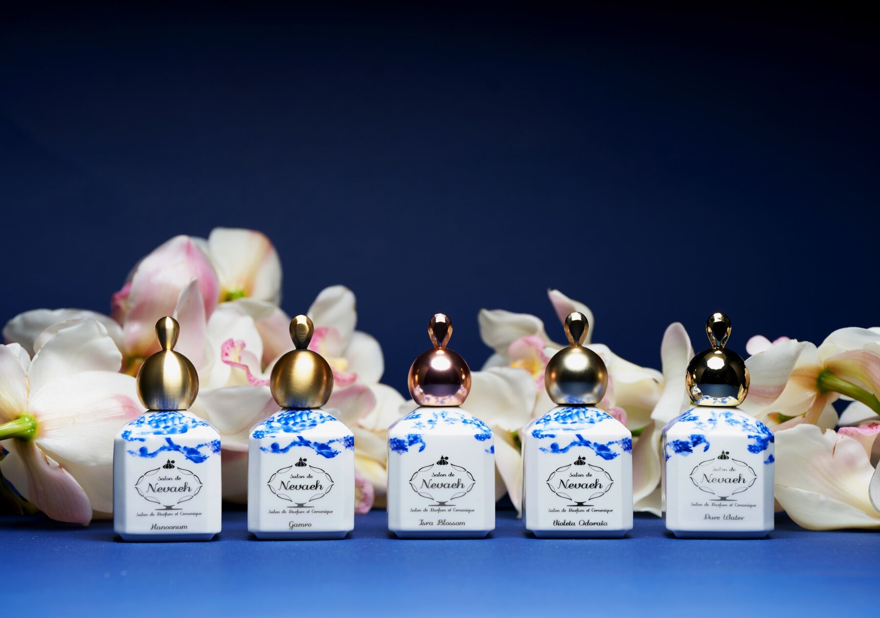 The Salon De Nevaeh perfumes in a line against a dark backdrop