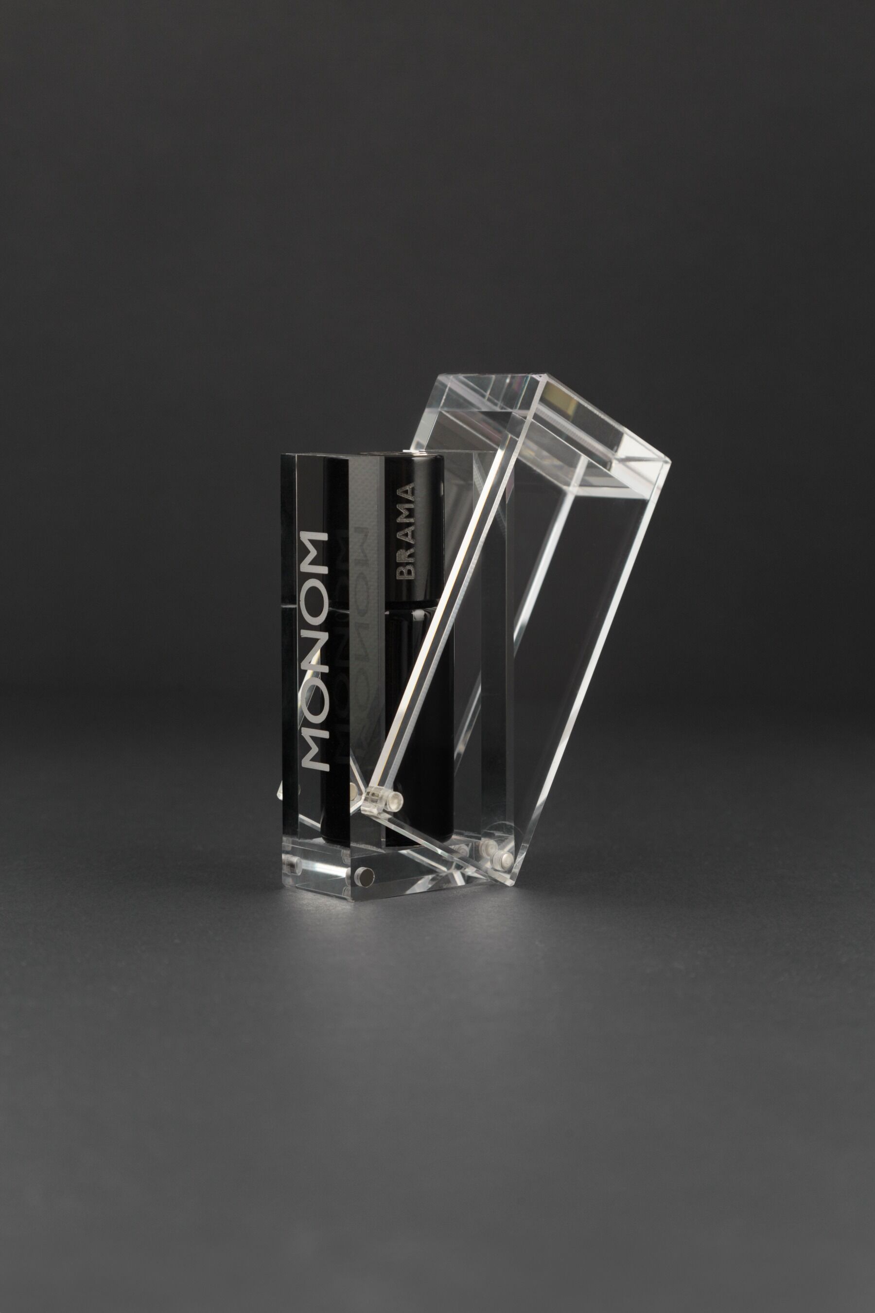 A black and white photo of a Monom perfume box showing the opening mechanism