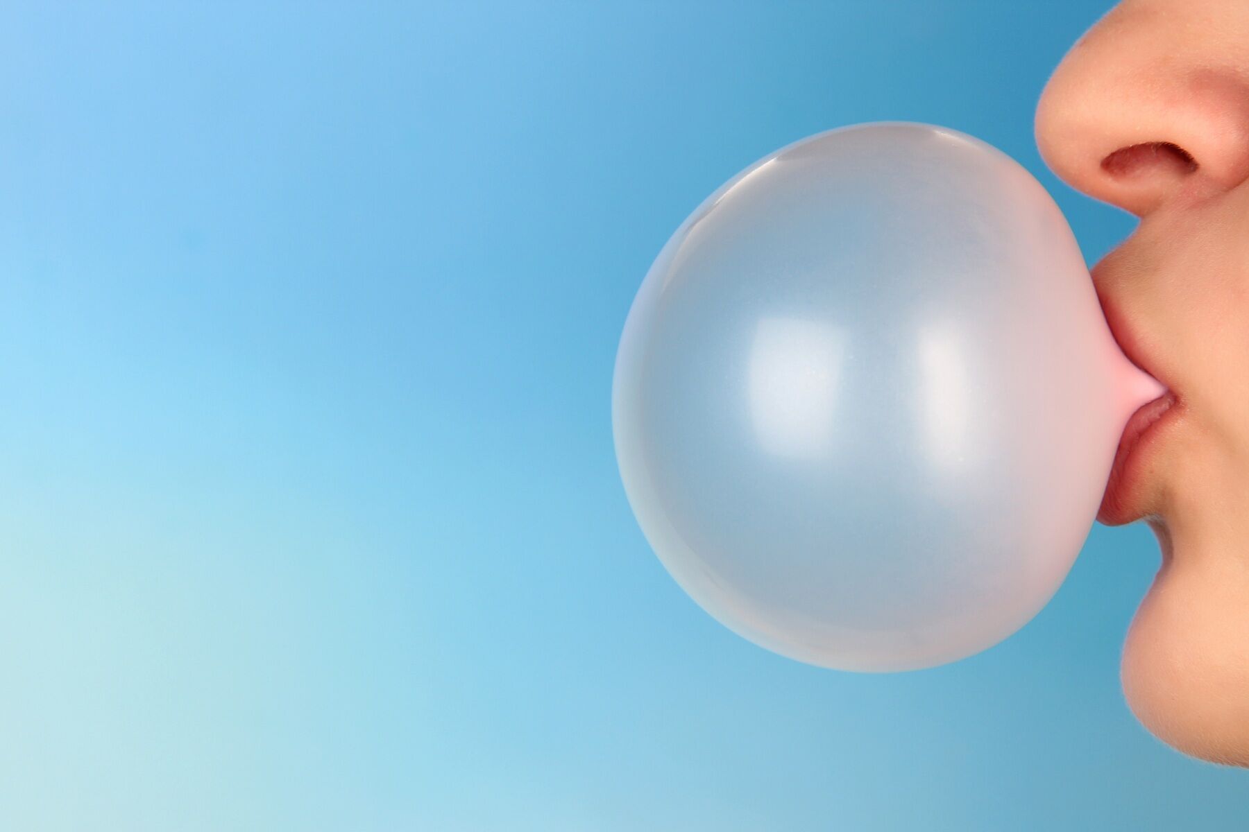 A woman's lips blowing a bubble of bubble gum