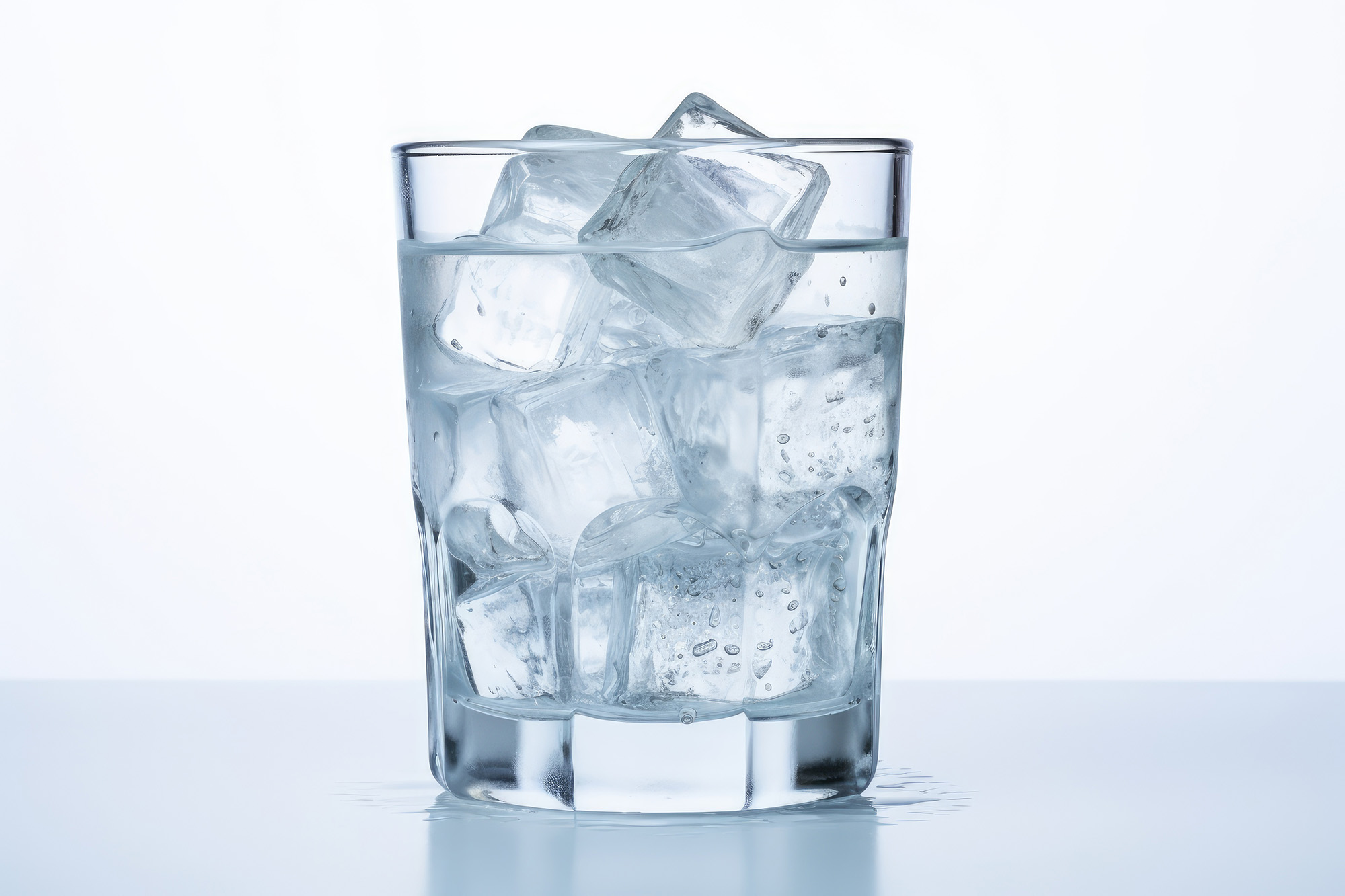 Glass of seltzer with ice cubes against a white background.