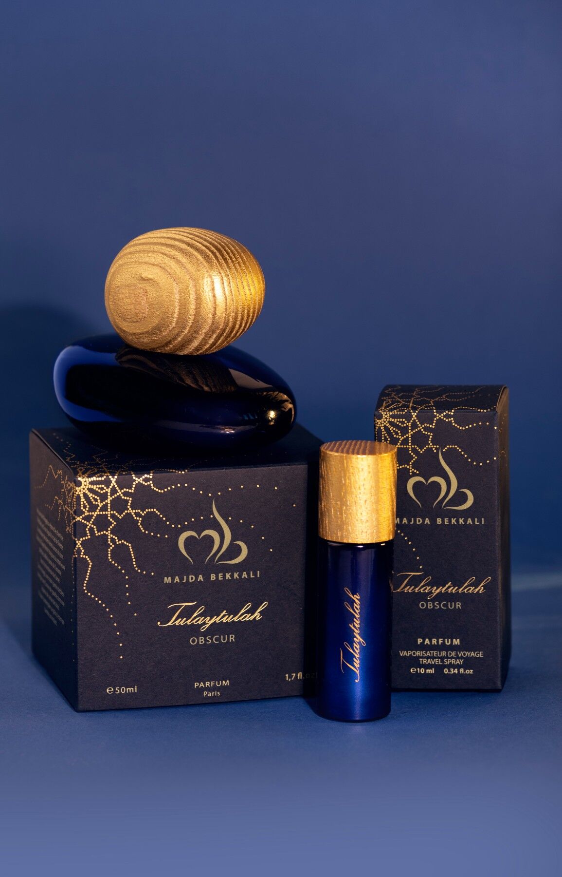 Tulaytulah Obscur perfumes in 50ml and 10ml size on their outer boxes against a blue backdrop