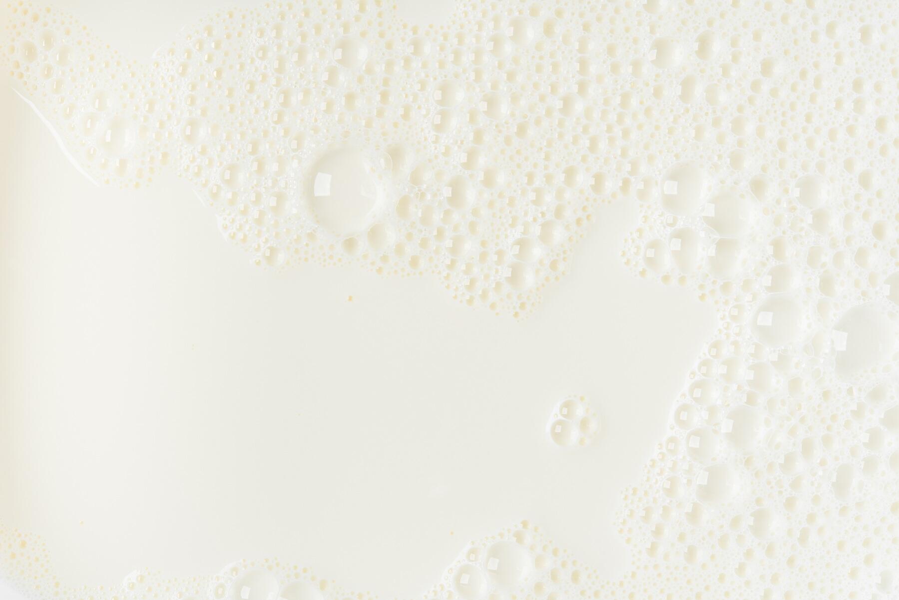 A close up of milk showing an off white texture and bubbles on the surface
