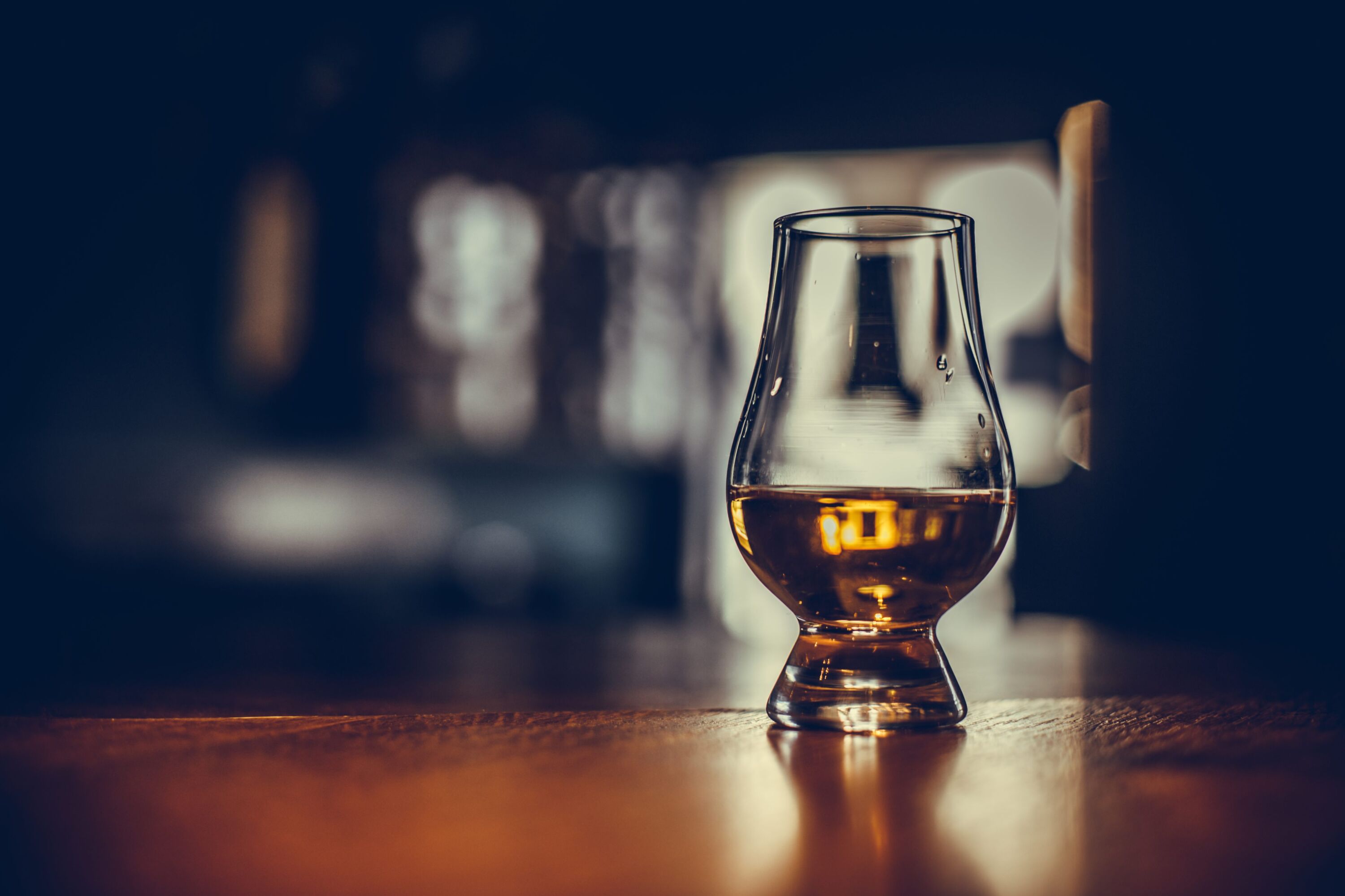 A whisky glass set on a wooden bar