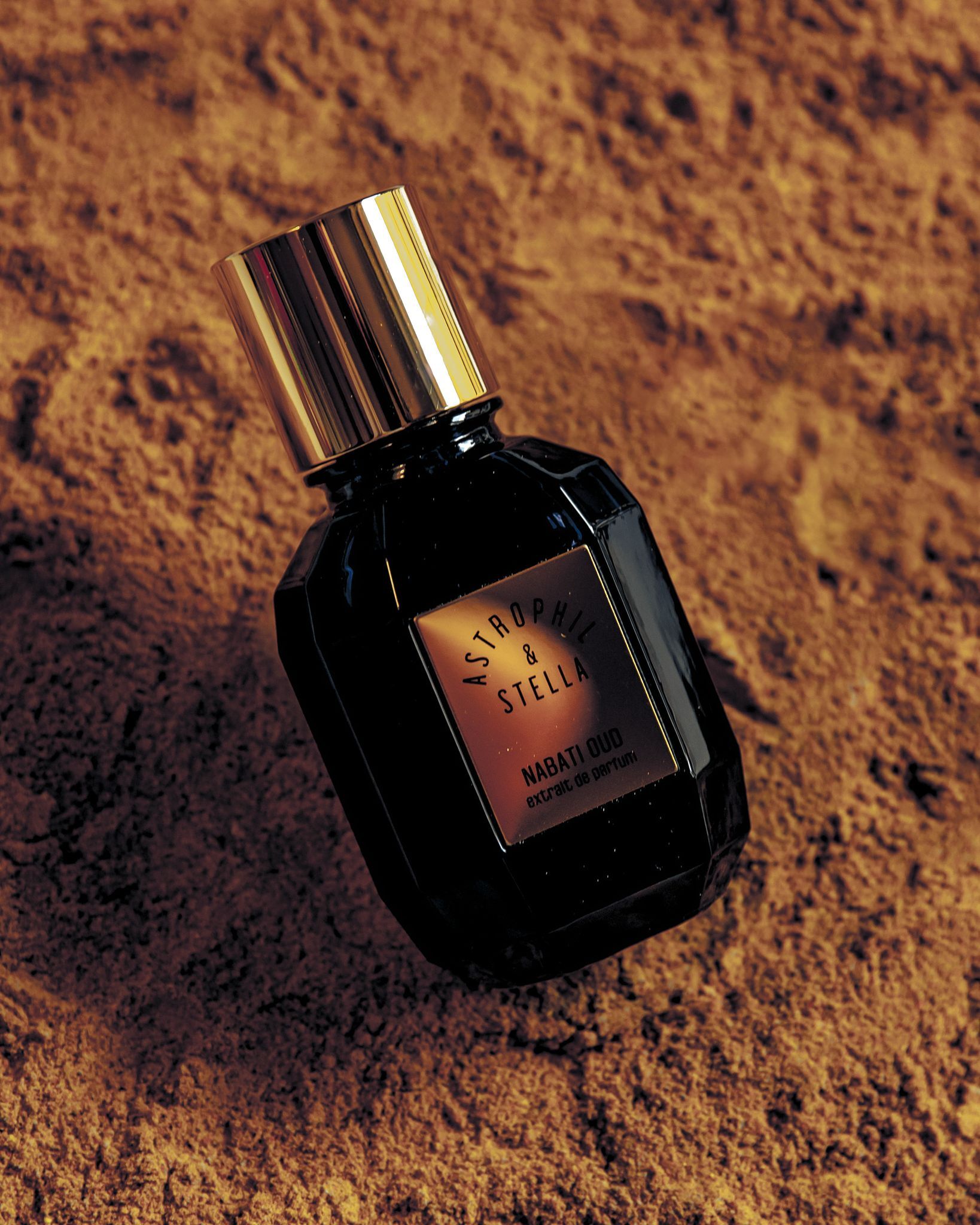 A bottle of Nabati Oud stood on golden brown sand