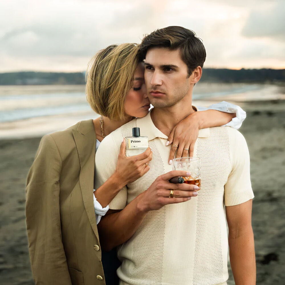 Primo perfume guy and woman at the beach with a bottle.
