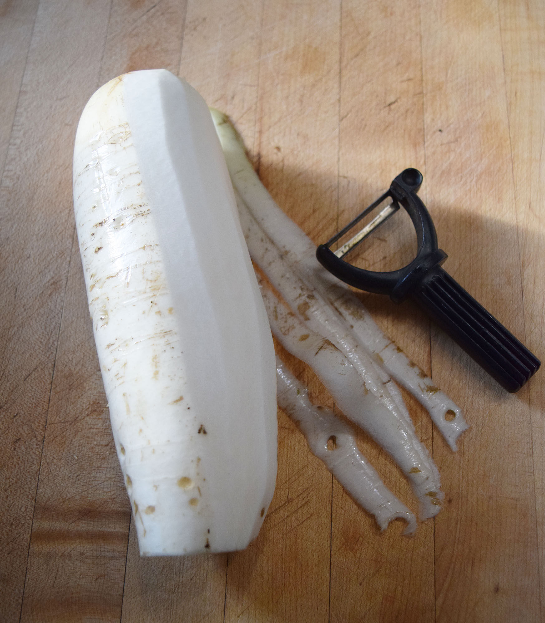 Daikon root, peeling.