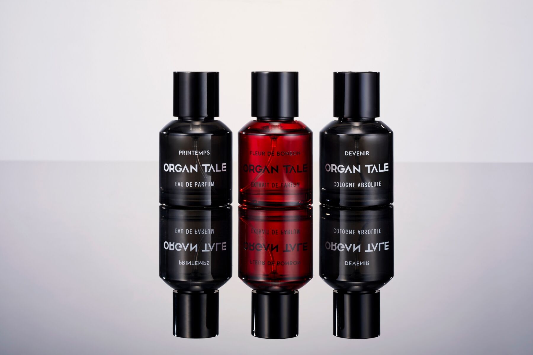 Three Organ Tale fragrances stood on a reflective surface or mirror so we see them in duplicate