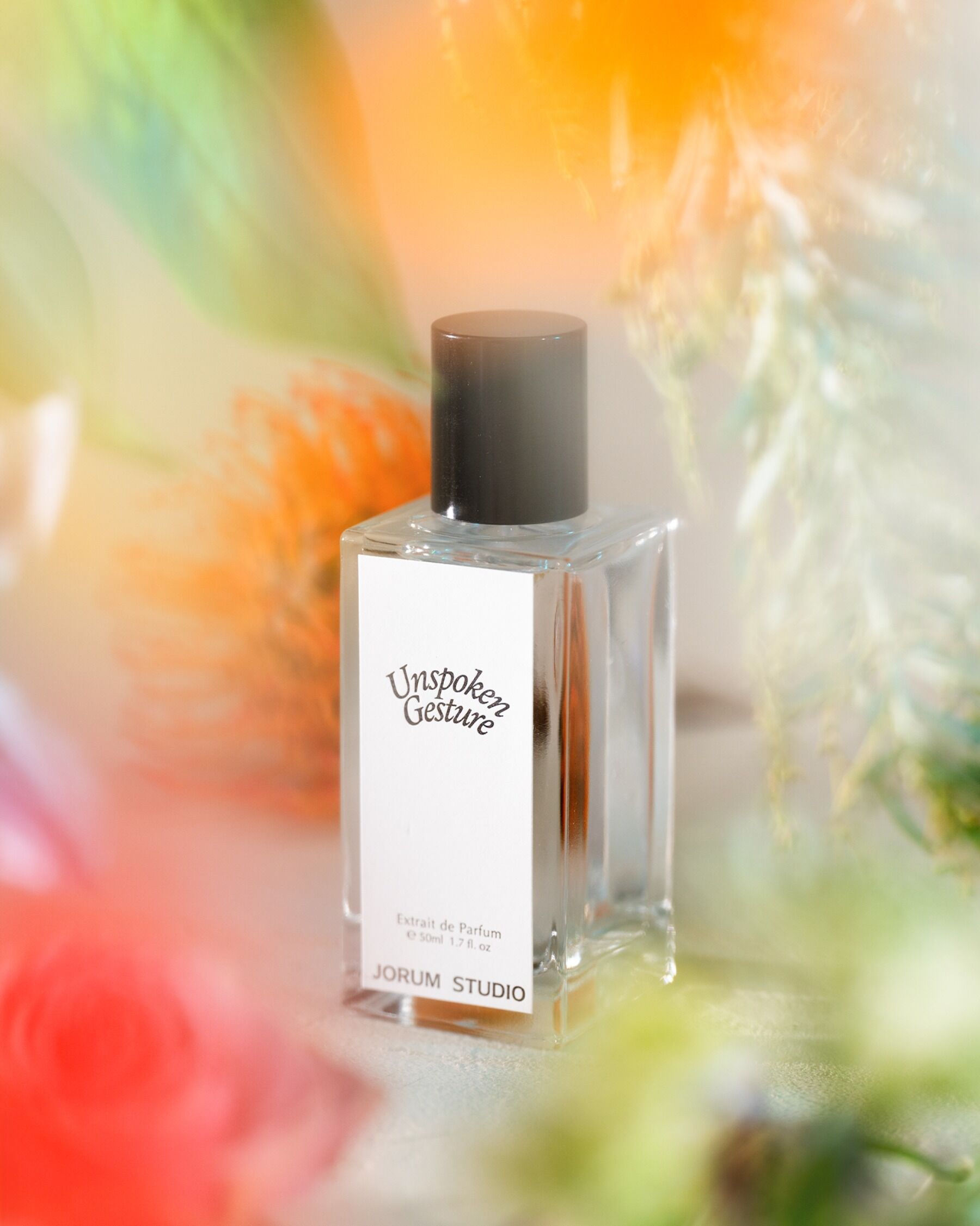 Unspoken Gesture perfume surrounded by out of focus flowers
