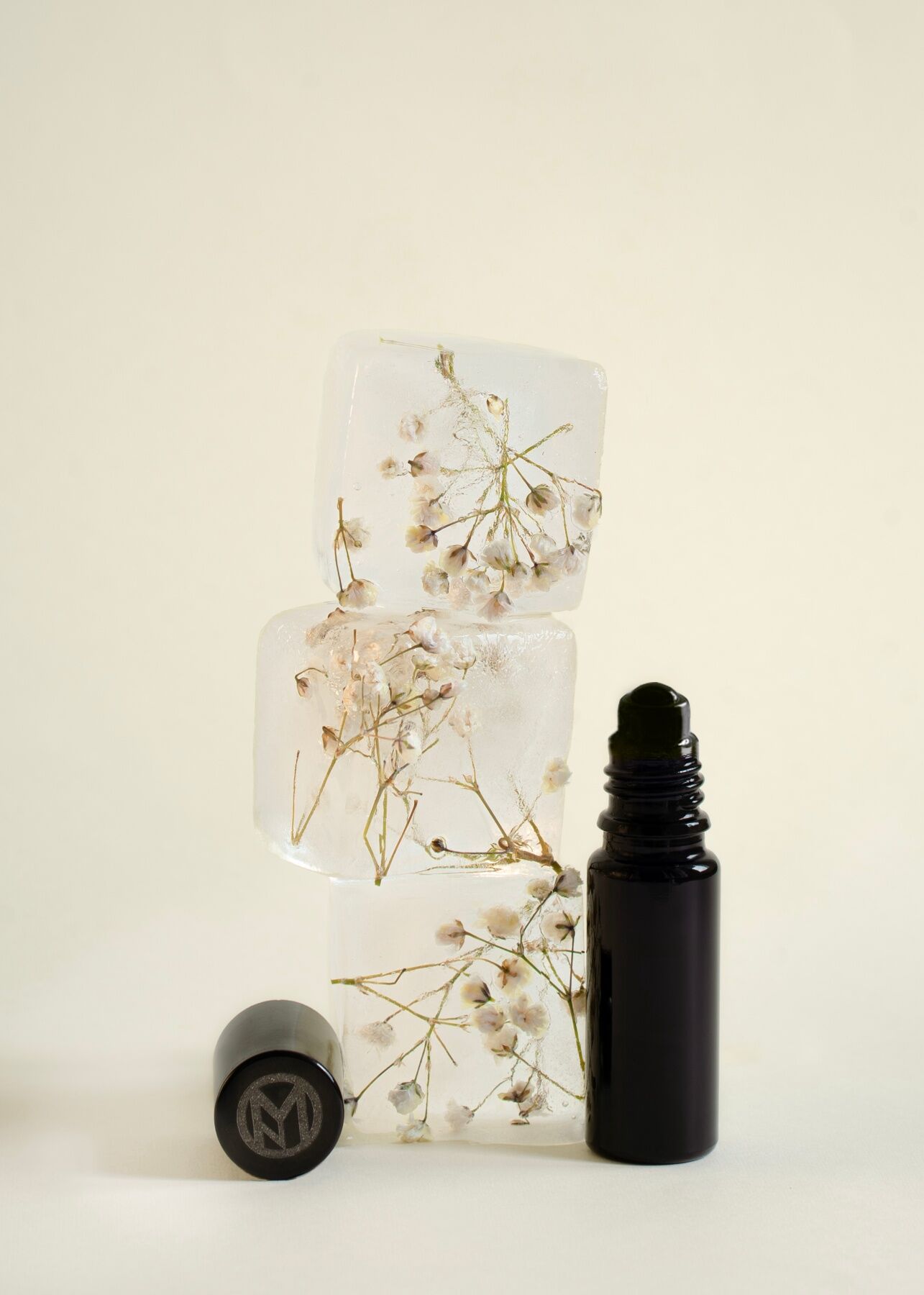 A bottle of Chloride next to cubes that look like ice with flowers frozen into them - the cap of Chloride is off and placed next to the blocks