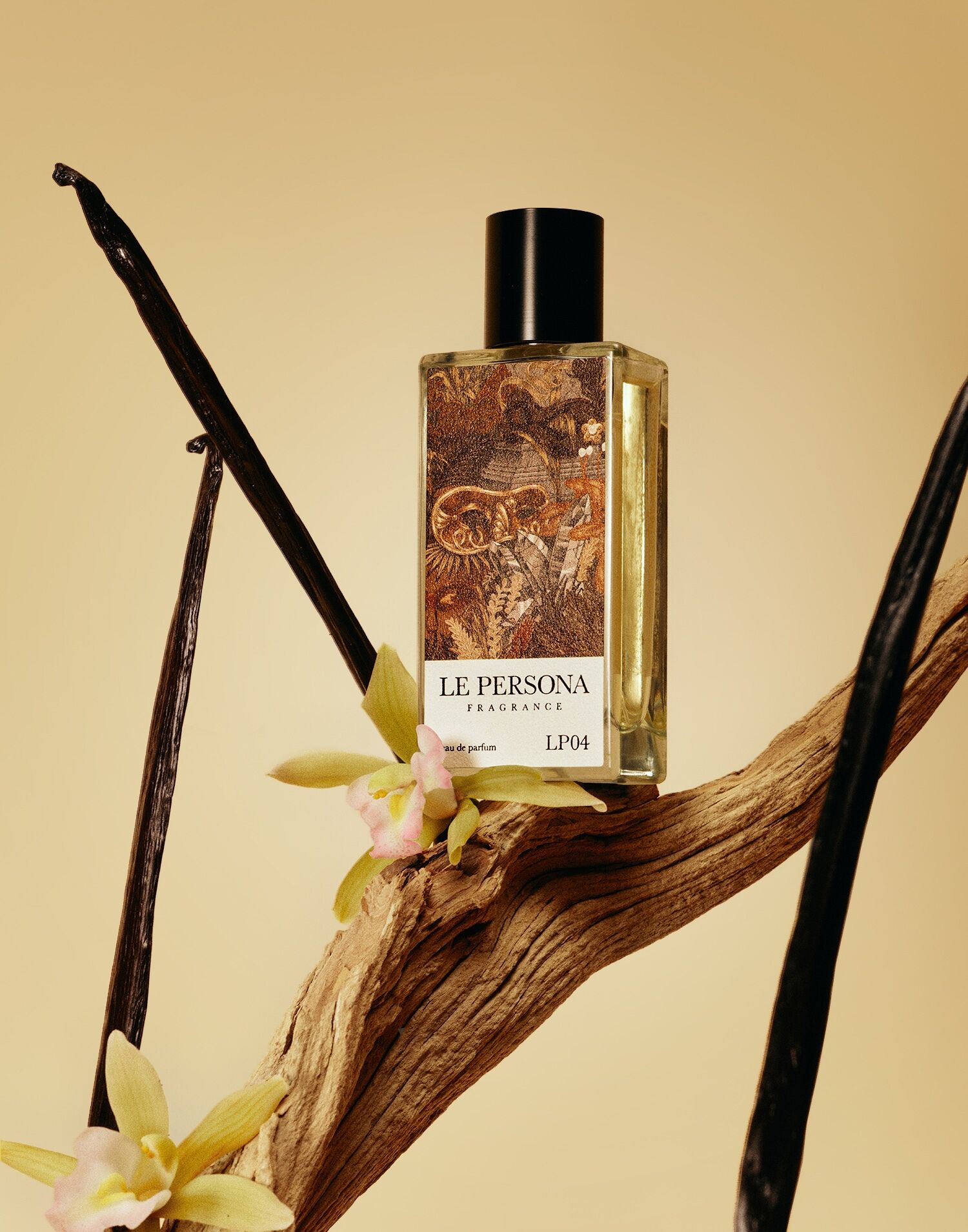 La Personas Golden Gem shown on a yellow backdrop with sticks of vanilla and orchid flowers