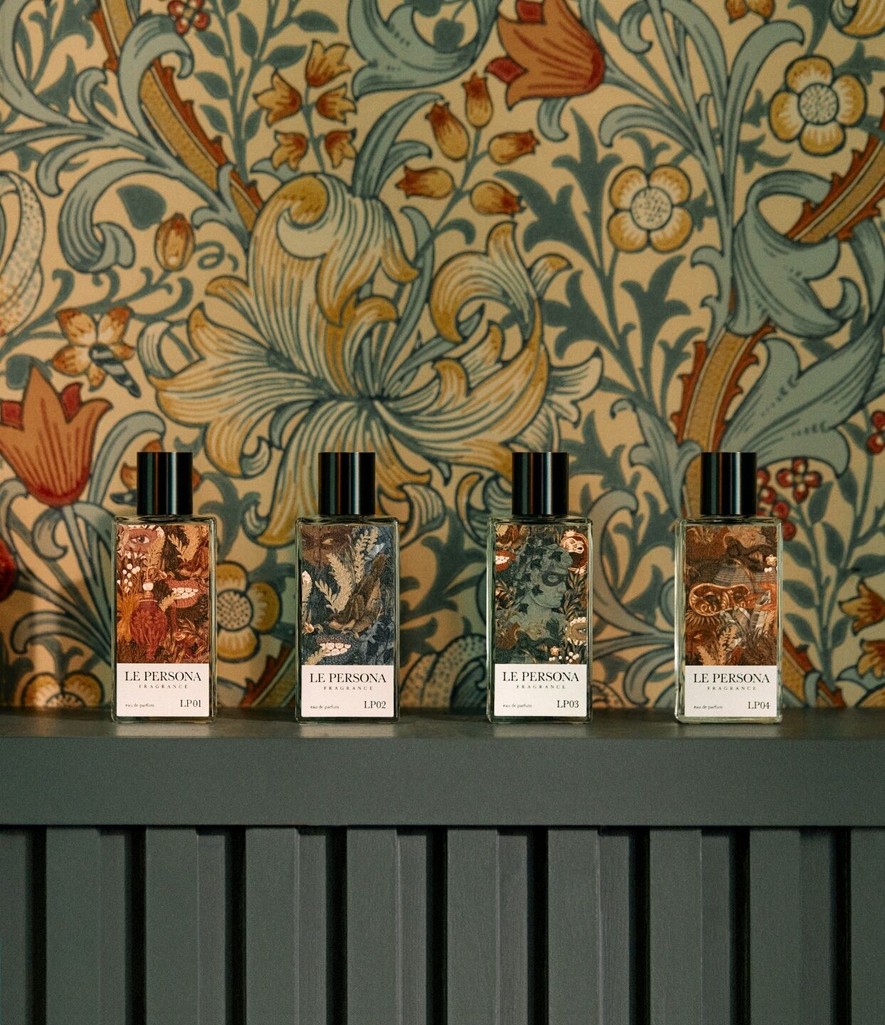 A group of La Persona scents against bold wallpaper and stood on a green shelf
