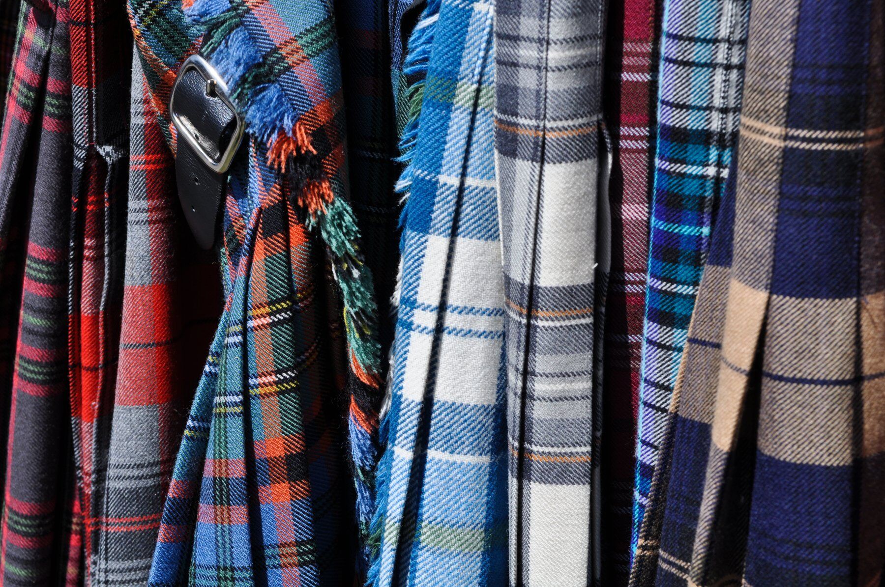Brightly coloured tartan cloth in a row showing different patterns