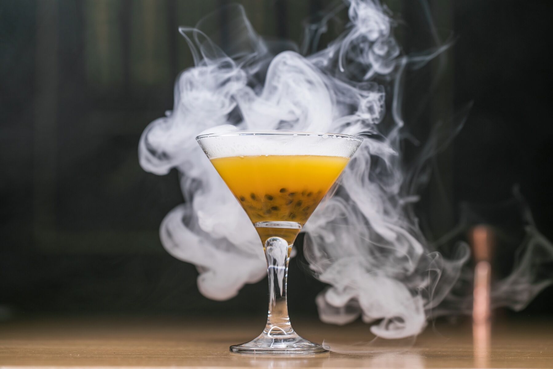 A cocktail glass with juice in it covered in smoke