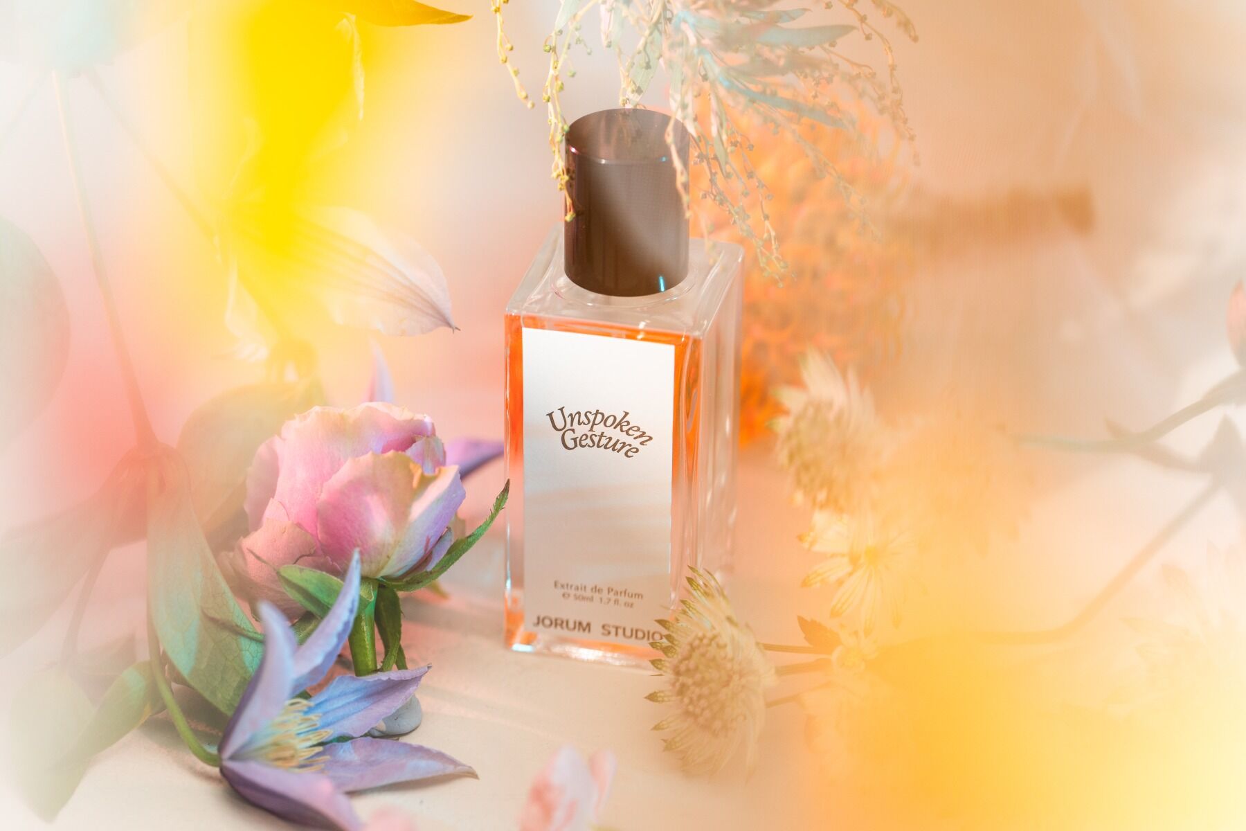 Unspoken Gesture perfume surrounded by flowers out of focus