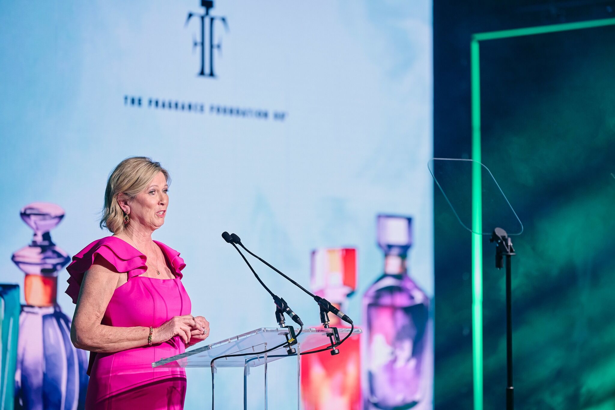 Linda Key Jackson dressed in pink, on stage, giving a speech at a lectern