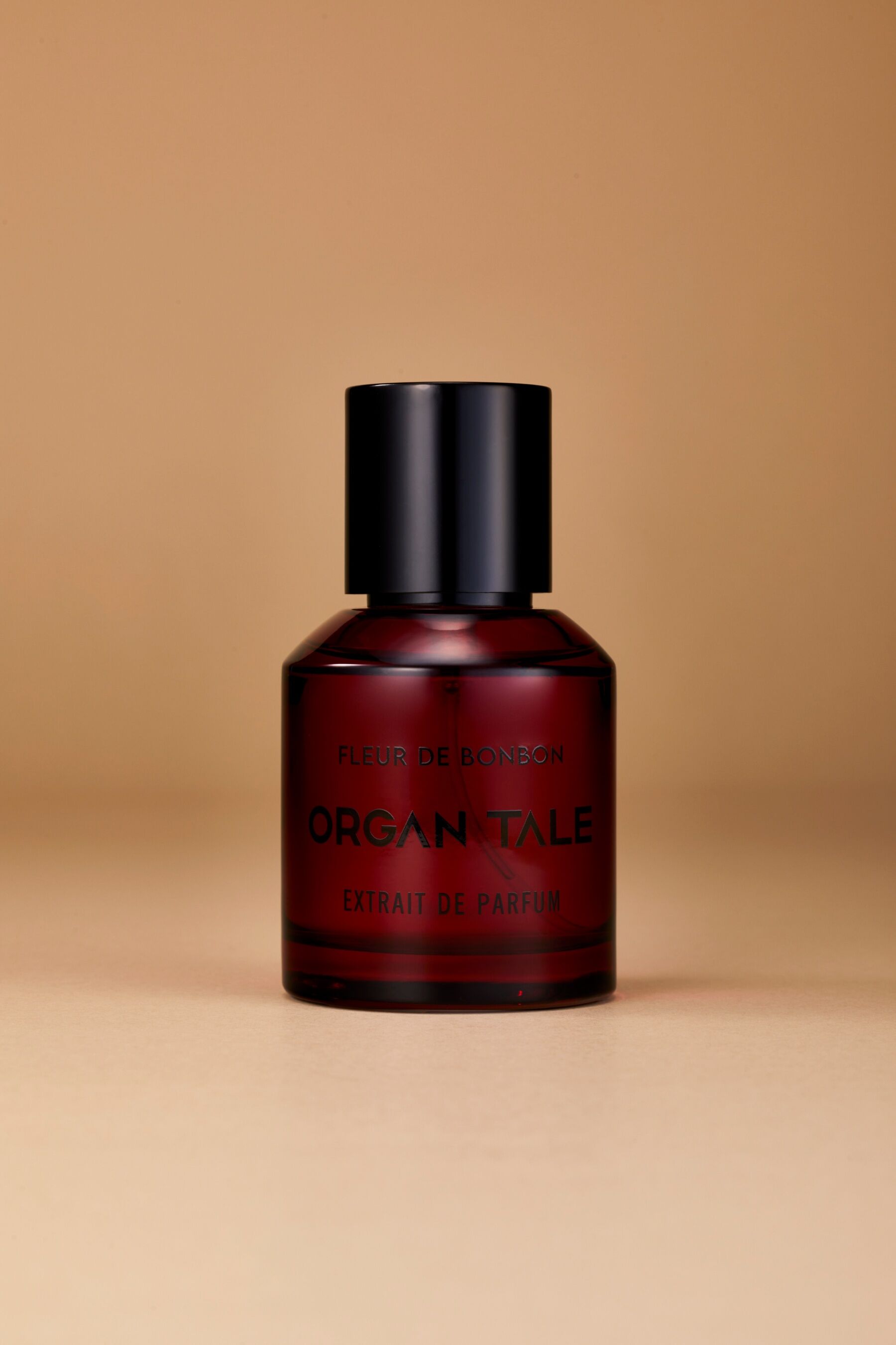 A bottle of Fleur de Bonbon by Organ Tale stood against a pink backdrop