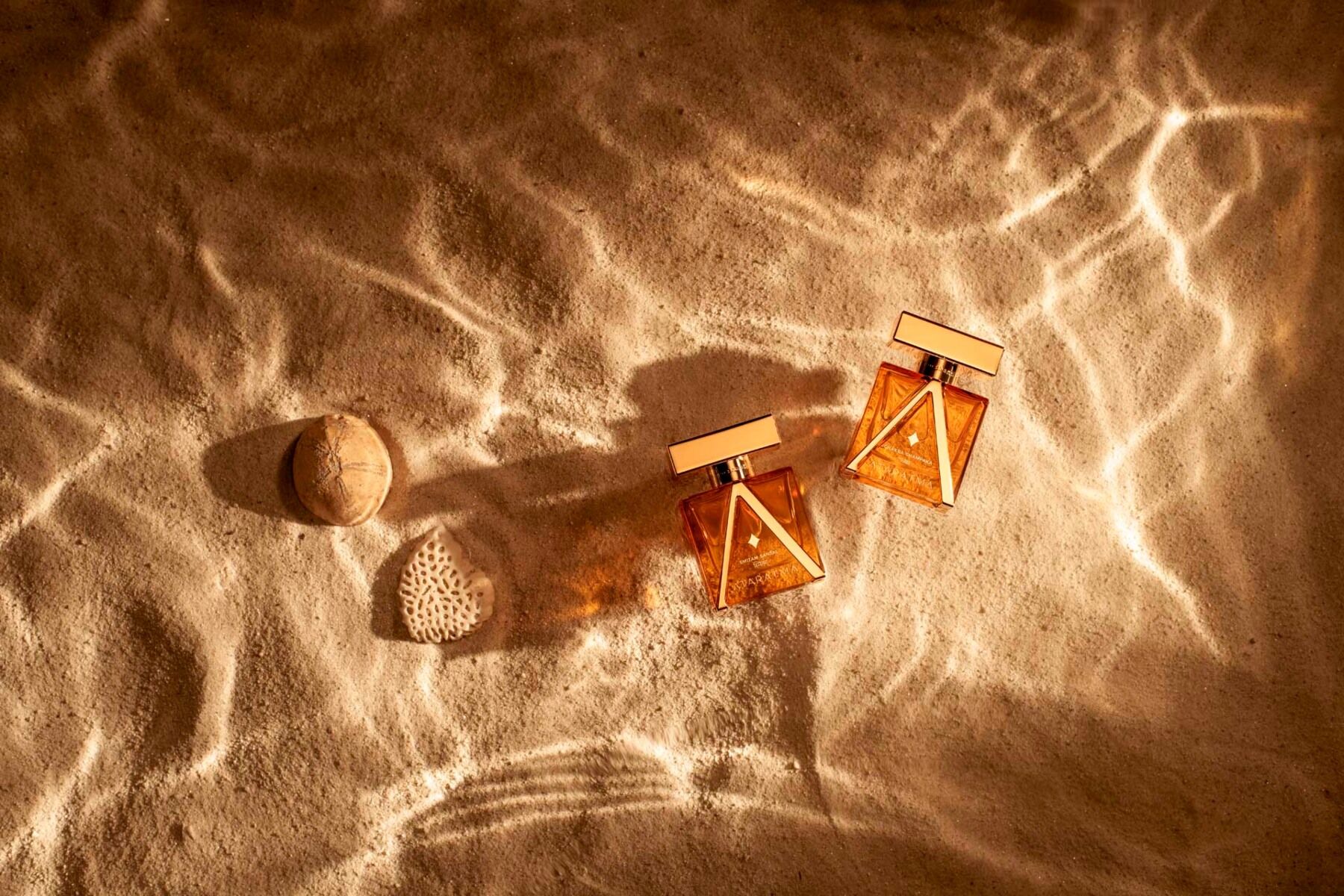 Two fragrances from Ataratma on sand with dappled light