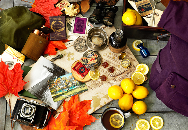 mix of odds and ends, autumn leaves, books, binoculars, tea cup with tea and citruses floating